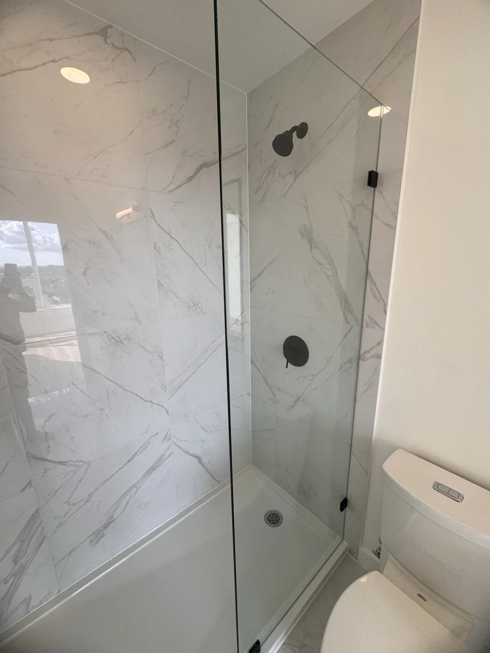 Glass shower with marble tiles, spotless after cleaning