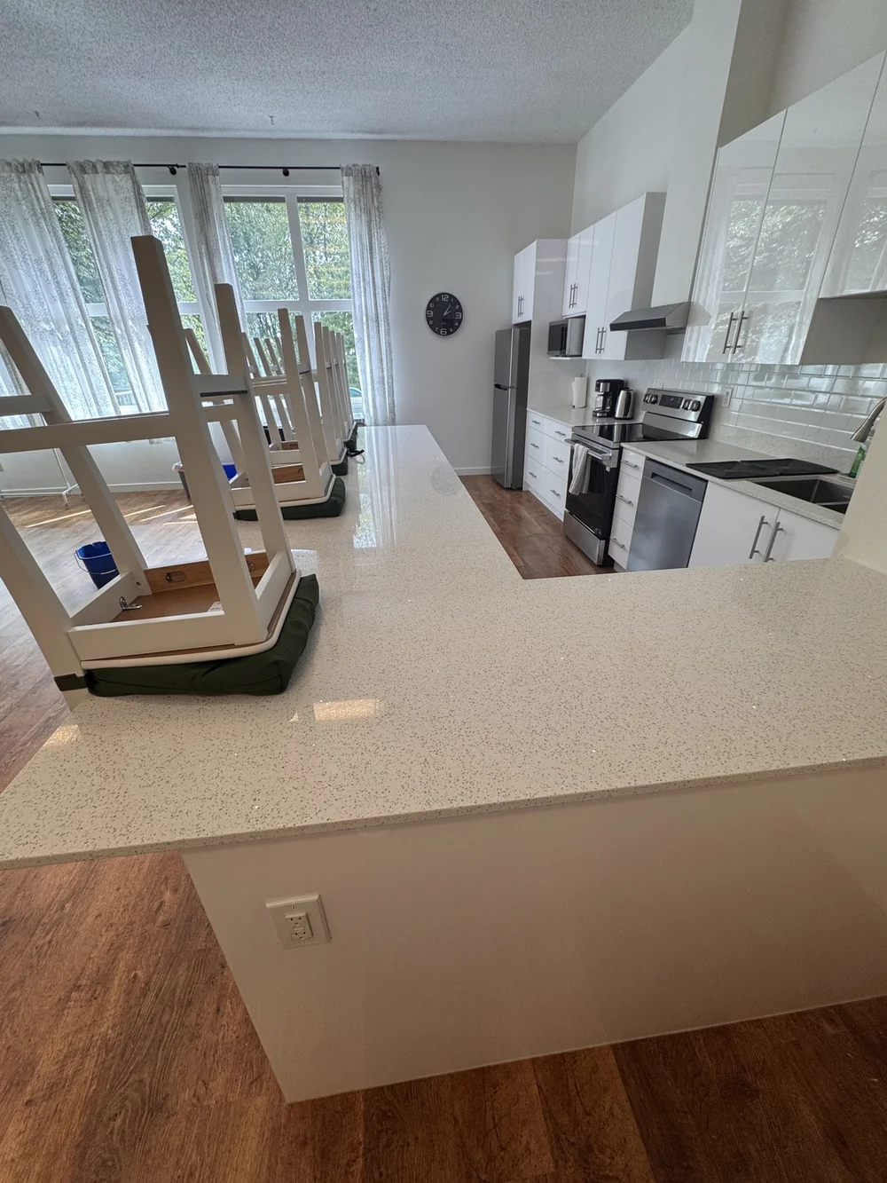 White kitchen mid move-out clean, chairs up and counters gleaming