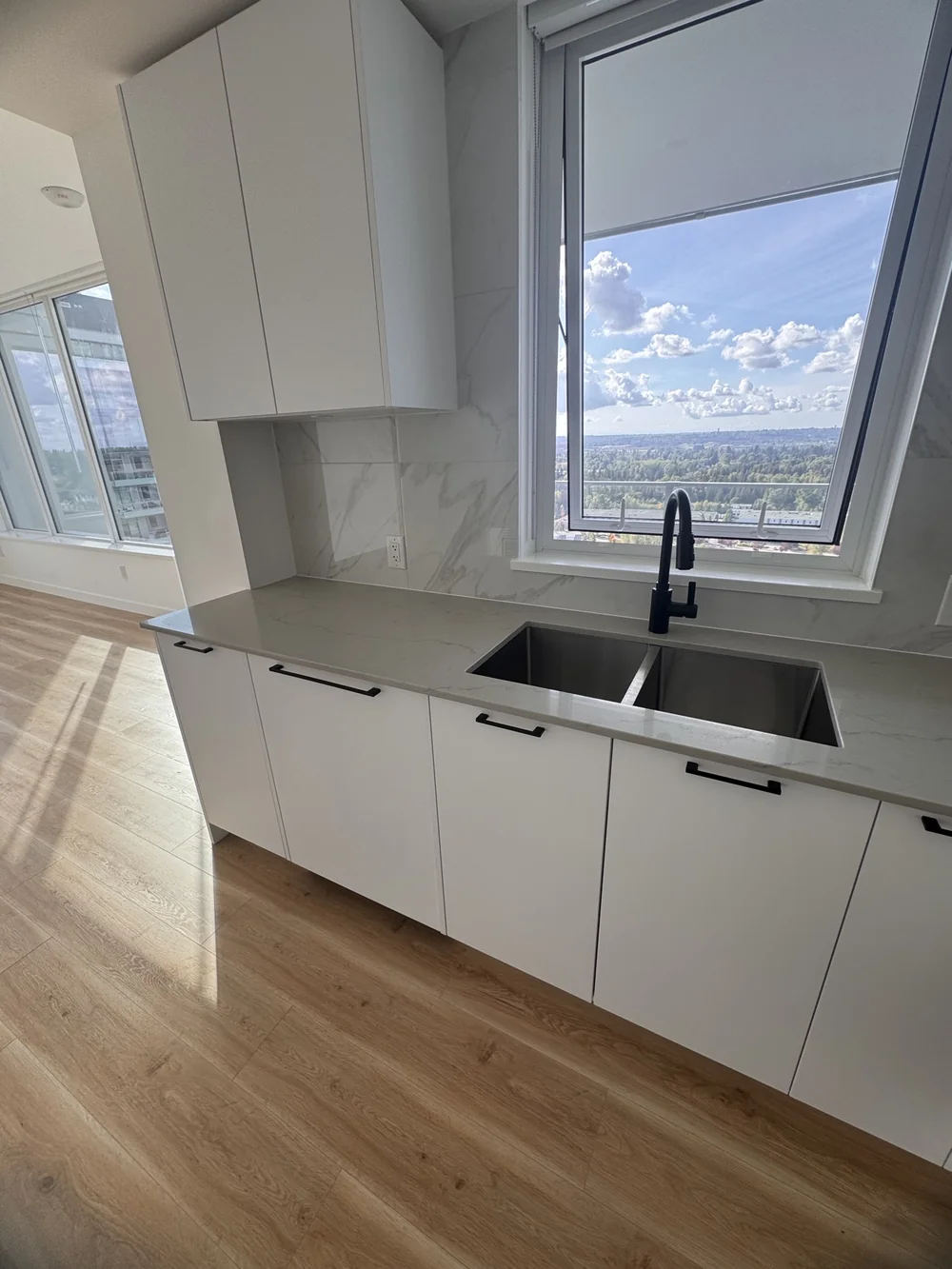 White kitchen with a sparkling sink under a large window